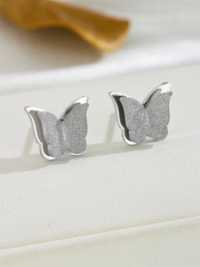Detail view of silver butterfly stud earrings with frosted texture and polished edges