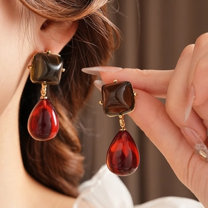 Primo piano di orecchini vintage in resina marrone e rossa indossati da una modella