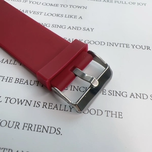 Close-up of red silicone watch strap with silver metal buckle on printed paper