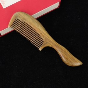 Natural green sandalwood hair comb with thick handle and fine teeth on black felt
