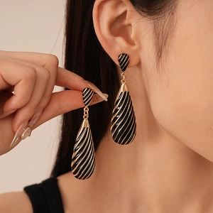 Detail of vintage teardrop zebra stripe earrings with gold base and black enamel finish