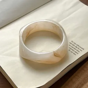 Detail of marble pattern resin bangle with brown swirl texture on an open book