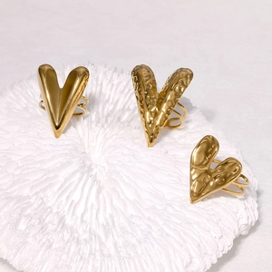 Detailed view of gold stainless steel heart rings with hammered and polished finishes