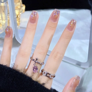 Elegant silver rings with pink teardrop crystal and chain link design on hand