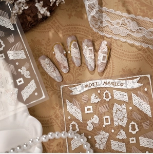 Macro view of white 3D relief lace nail stickers with floral pearls and vintage texture