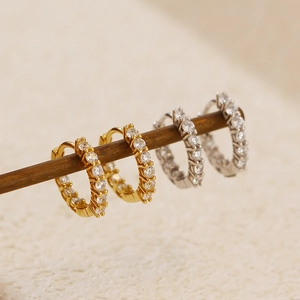 Macro shot of silver and gold hoop earrings featuring a single row of clear zircon stones