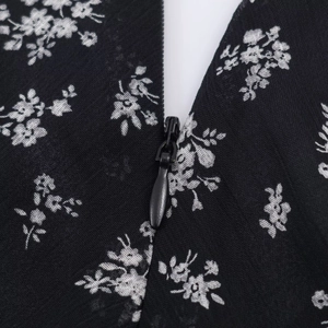 Detail shot of a black floral dress featuring a high-quality hidden nylon zipper closure