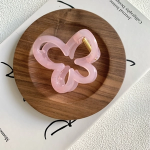 Close-up of pink flower hair claw clip on wooden tray with aesthetic INS style magazine