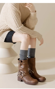 Détail de bottes mi-mollet marron à boucles et chaussettes montantes en tricot gris