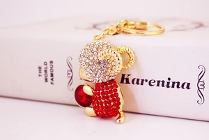 Close-up of golden sheep keychain with red and clear rhinestones on a white book