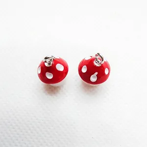 Macro detail of red resin mushroom charms with white dots and silver hanging rings