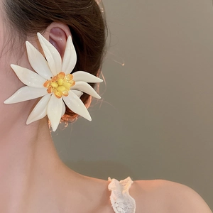 Detail of white resin floral earring with yellow center worn on model's ear