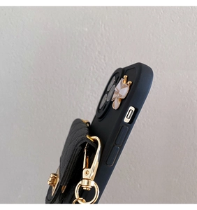 Detail of black quilted pouch attachment with gold butterfly accent on iPhone case