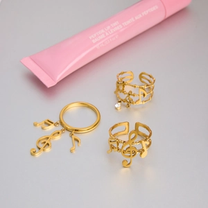 Detailed top view of 18K gold plated musical note ring set on brushed metal surface