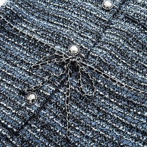 Détail macro du tissu en tweed bleu avec boutons argentés et décoration de chaîne noire