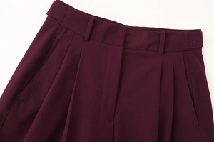 Detailed close-up of dark wine red trousers showing fabric texture and pleat details