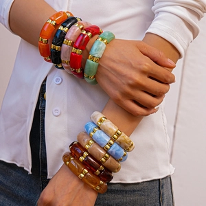 Detail of stacked colorful bamboo-style acrylic resin bracelets with gold spacers