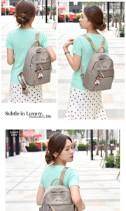 Outdoor shot of small Oxford fabric backpack in khaki with cute bear charm and metal logo