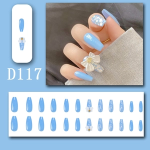 Detail of sky blue press-on nails with 3D white bows and pearlescent glitter accents