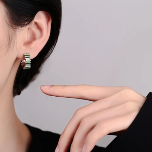 Elegant C-shaped silver earrings with emerald green rectangular stones on model