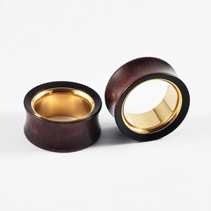 Detail of dual-tone hollow ear gauges featuring dark wood outer and golden metal inner ring