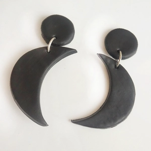 Handmade black crescent moon clay drop earrings with minimalist round stud on white background
