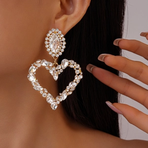 Close-up of oversized heart-shaped rhinestone earrings with elegant silver finish and crystals