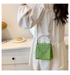 Detail of green textured mini crossbody bag with silver chain and metal ring handle