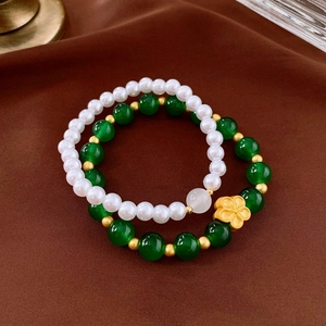 Detail of 2-piece set with green glass beads, pearls, and a gold flower charm on velvet