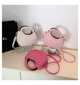 Close-up of pleated leather handbags in white, pink and magenta with round cut-out handles