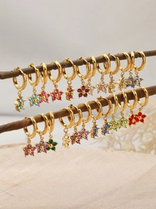 Close-up of gold-plated flower earrings with colorful rhinestones on a wooden branch