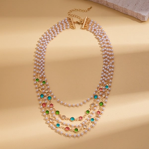 Detail of baroque layered necklace with faux pearls, colored gems, and golden clasp
