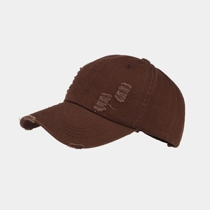 Close-up of distressed vintage brown baseball cap featuring ripped details and washed cotton