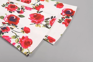 Gros plan d'un imprimé rose rouge sur tissu blanc avec des coutures détaillées