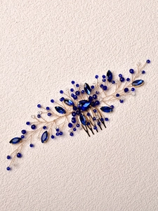 Macro detail of handmade bridal hair comb with emerald crystals and gold wire branch work