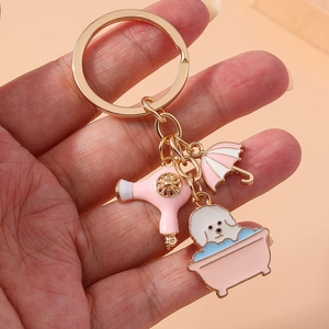 Detail of metal keychain featuring enamel pink hair dryer, umbrella, and dog in a bathtub