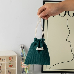 Close-up of deep green corduroy drawstring pouch with white cotton ropes and label