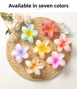 Macro detail of seven colorful 8cm plumeria flower hair claws on a woven mat