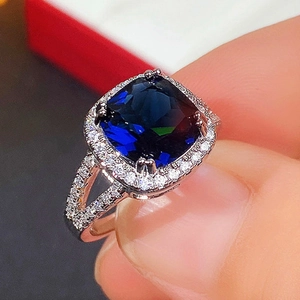 Detailed macro view of silver ring featuring square blue gemstone with halo setting