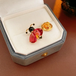 Macro shot of vintage enamel bee brooch with red zircon in a luxury velvet jewelry box