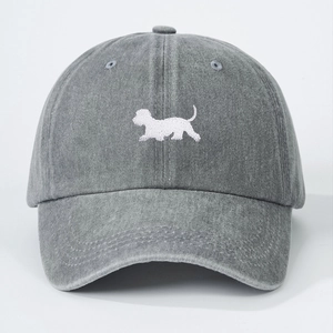 Close-up of a gray washed denim baseball cap with a white embroidered puppy pattern
