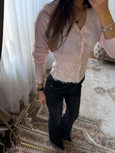 Detail eines rosa Strick-Cardigans mit exquisitem weißem Saum aus Spitze und Knopfleiste