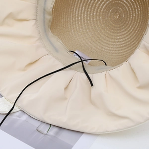Hollow knit sun hat with wide brim and bow, showing interior texture and windproof cord