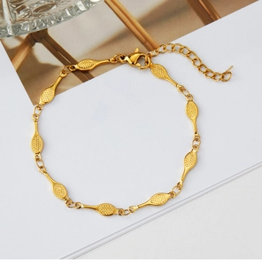 Macro view of gold tennis racket chain bracelet with grid texture and lobster clasp