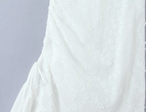 Détail d'une robe blanche avec broderie anglaise florale et cordon de serrage