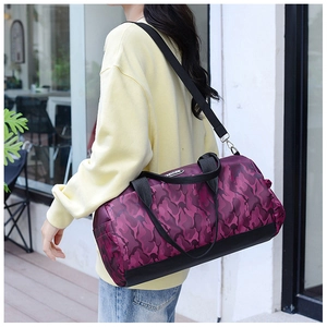Detailed view of purple camo travel duffel bag with wide shoulder strap worn crossbody