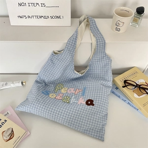 Detail of blue and white checkered tote bag with colorful Pearl Sozakka embroidery