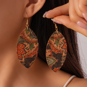 Close-up of Bohemian leather leaf earrings with vintage floral patterns on a female model