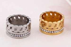 Dettaglio di anelli geometrici traforati con cristalli bianchi in finiture oro e argento
