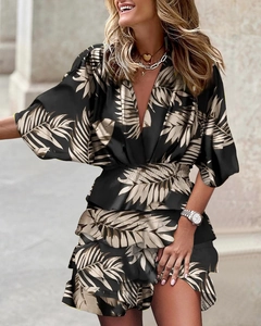 Detail of V-neck and ruffled hem on black dress with beige leaf print pattern